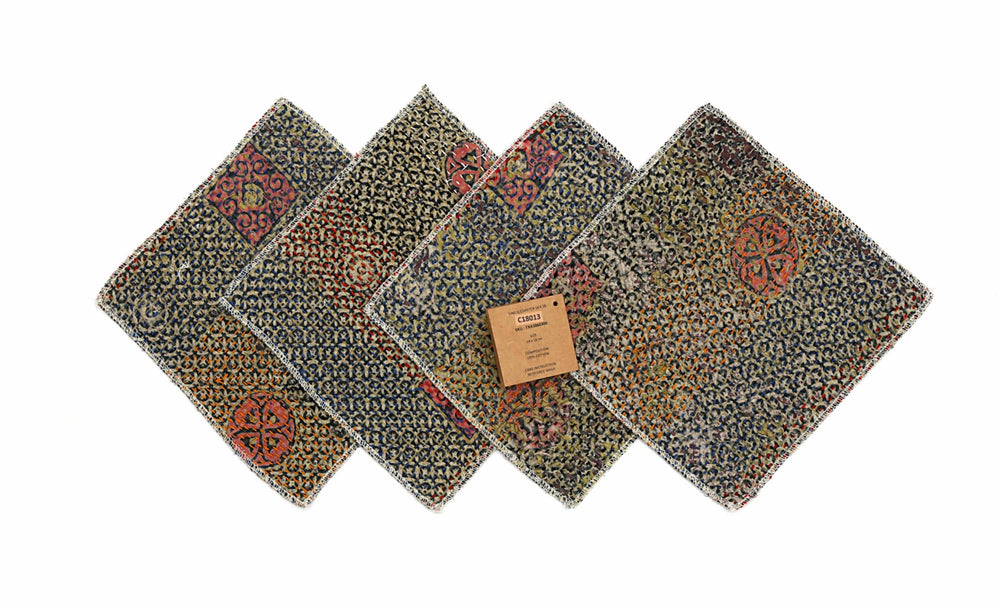 Sæt med 4 bordskånere i 18x18 cm med blå vævet mønster og farverige orange/røde abstrakte ornamenter, kantet med hvid frynse