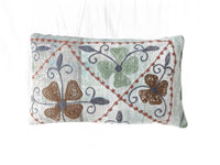 Einzigartiger Suzani-Kissenbezug 30x50 cm mit weißem Grund und gestickten Herzen und Trageornamenten in Blaugrün, Terrakotta und Dunkelblau im Vintage-Boho-Stil.